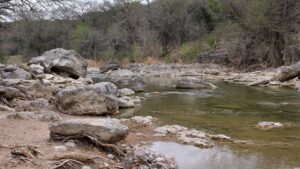 Limestone boulders and shallow green water along the Pedernales River in the Texas Hill Country